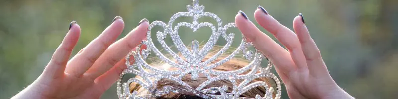 A princess tiara on a head being held by hands.