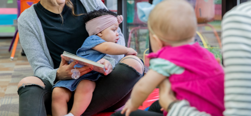 Two toddlers being read a story.